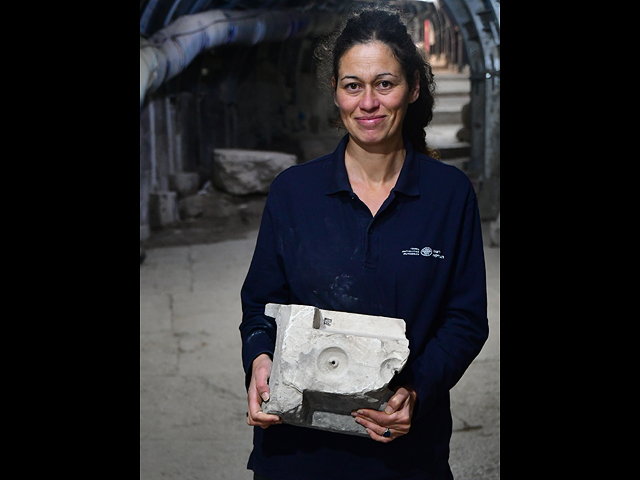 Археолог Елена Махлин держит в руках фрагмент столешницы