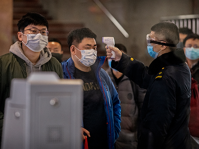 Китайский пассажир, который только что прибыл из Ухани в Пекин, проверяется на медицинским работником на Пекинском железнодорожном вокзале. 23 января 2020 года, Пекин, Китай