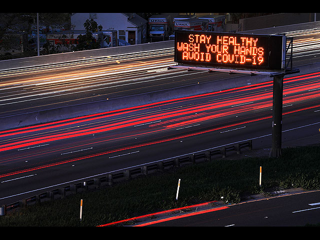 Надпись на дорожном указателе: "Будьте здоровы, мойте руки, избегайте COVID-19"