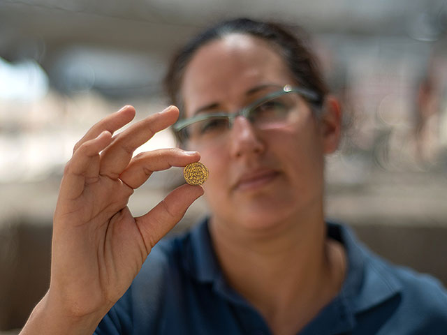 Лиат Надав Зив держит золотую монету из клада. Управление древностей Израиля