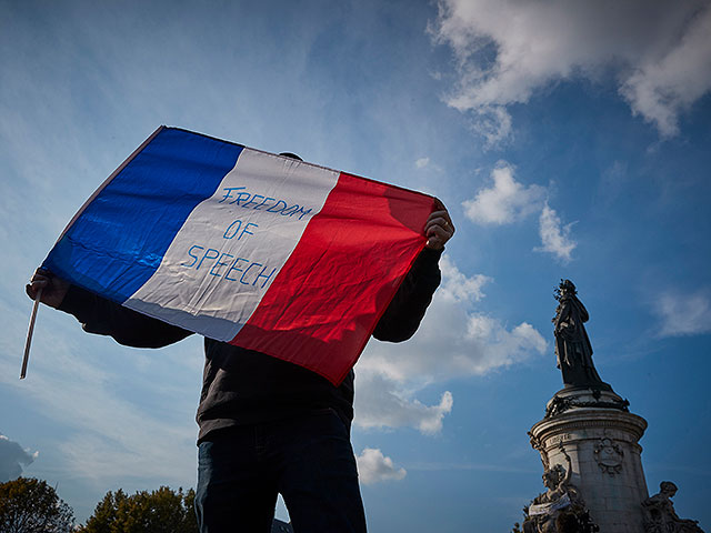 Демонстрант с французским трехцветным флагом с надписью "Свобода слова" во время акции протеста в память об убитом школьном учителе Сэмюэле Пати, погибшем в результате теракта в пригороде Парижа. 18 октября 2020 года, Париж