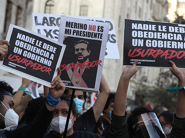 Протестующие против смещения президента Мартина Вискарры держат плакаты с изображением нового президента Перу Мануэля Мерино и посланием по-испански: "Он не мой президент" во время демонстрации на площади Сан-Мартин в Лиме, Перу, 12 ноября 2020 года