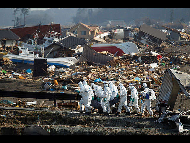 Полицейские несут тело найденное в районе, разрушенном землетрясением и цунами 11 марта. Намие, префектура Фукусима, северо-восток Японии, 15 апреля 2011 года