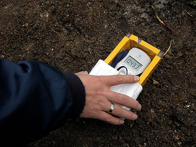 Рабочий проверяет уровень радиации у верхнего слоя почвы у частного дома в Фукусиме. 21 февраля 2012 года
