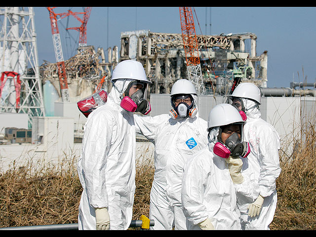 Представитель СМИ в сопровождении сотрудников TEPCO в защитных костюмах осматривает здания энергоблоков 3 и 4 пострадавших от цунами. 28 февраля 2012 года