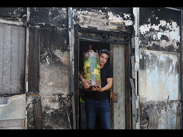 Израильтянин выносит свитки Торы из сожженной синагоги после ночных беспорядков. Лод, 12 мая 2021 года
