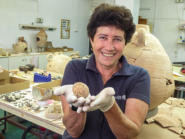 Археолог Алла Нагорски держит куриное яйцо, которому тысяча лет