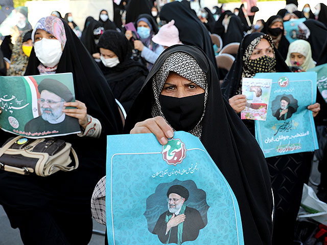 Сторонники кандидата в президенты Эбрагима Раиси держат плакаты во время митинга в Тегеране, Иран, 14 июня 2021 года