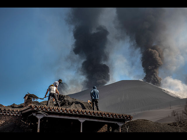 Жители очищают дом от толстого слоя пепла в Лас-Манчас на канарском острове Ла-Пальма, Испания. 14 октября 2021 года