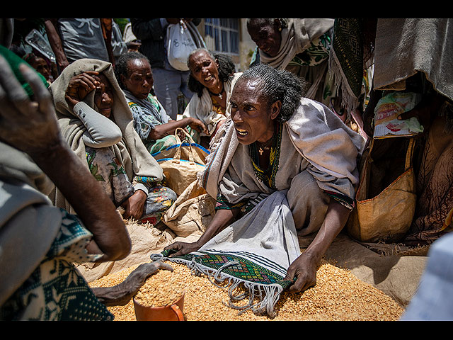 Женщина спорит с другими по поводу распределения гороха, раздаваемого Обществом милосердия Тыграя в городе Агула на севере Эфиопии, 8 мая 2021 года. По данным AP в раздираемом войной Тыграе многие умирают от голода