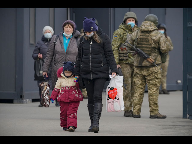 Женщина c ребенком пересекают линию разграничения контролируемую пророссийскими сепаратистами через единственный пункт пропуска, который открыт ежедневно. 11 февраля 2022 года