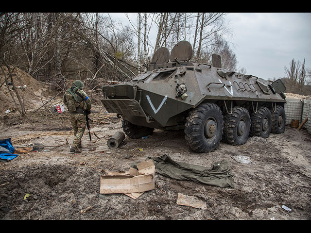 Украинский военнослужащий проходит мимо брошенной военной машины российской армии на дороге недалеко от Чернобыля