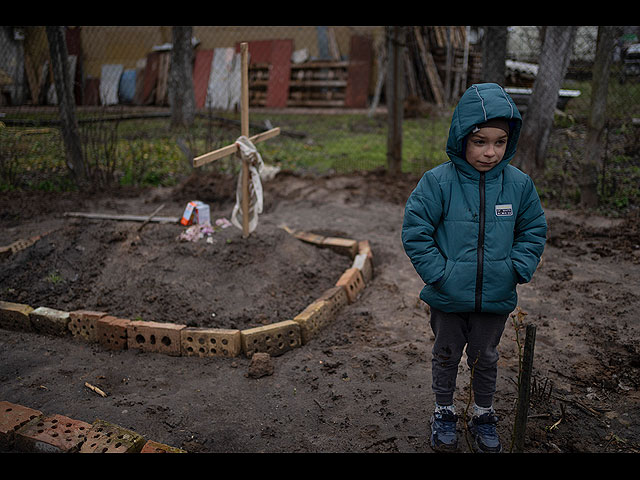 6-летний Влад Танюк во дворе своего дома возле могилы своей матери Марины, окраина Киева, 4 апреля 2022 года
