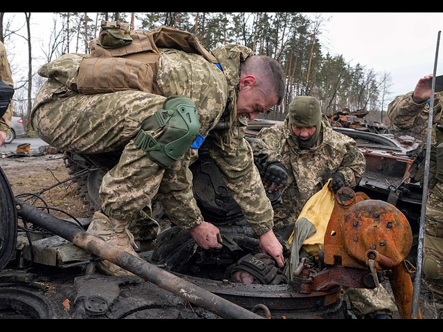 Украинские солдаты вытаскивают труп российского солдата из подбитого танка. Село Дмитровка недалеко от Киева, 2 апреля 2022 года