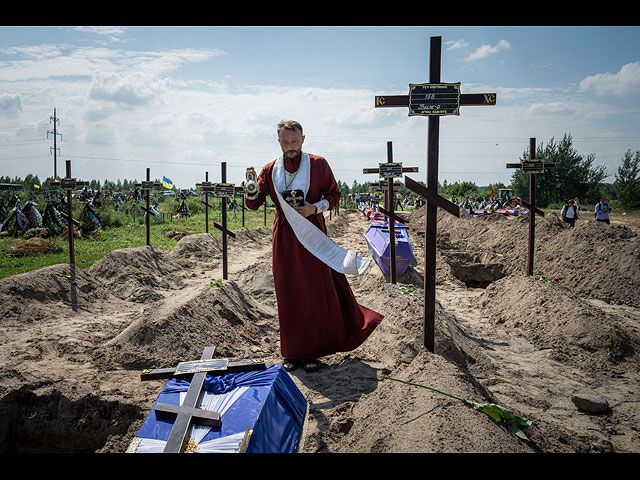 Священник Андрей у гробов неопознанных мирных жителей, убитых российскими войсками во время российской оккупации в Буче под Киевом, 17 августа 2022 года