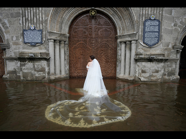 Невеста готовится войти в затопленную церковь Барасоайн на свою свадьбу в Малолосе, провинция Булакан, Филиппины, 22 июля 2025 года