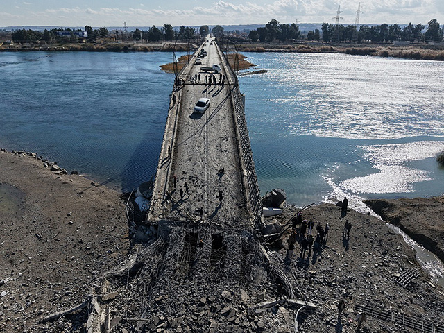 Люди переходят пешком поврежденный мост Аль-Рашид, разрушенный отступающими войсками "Сирийских демократических сил"