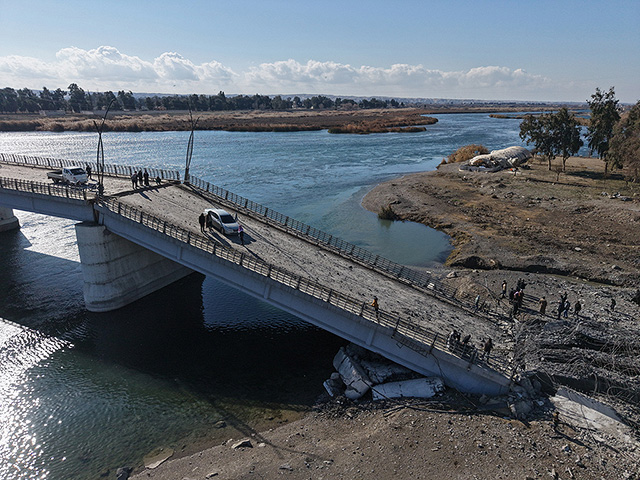 Люди осматривают поврежденный мост Аль-Рашид, после того как он был разрушен отступающими "Сирийскими демократическими силами"