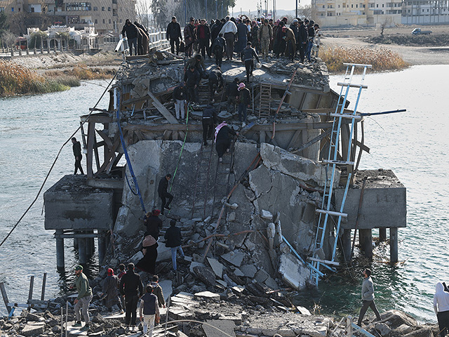 Люди перебираются через поврежденный мост Аль-Рашид, после того как он был разрушен отступающими "Сирийскими демократическими силами"