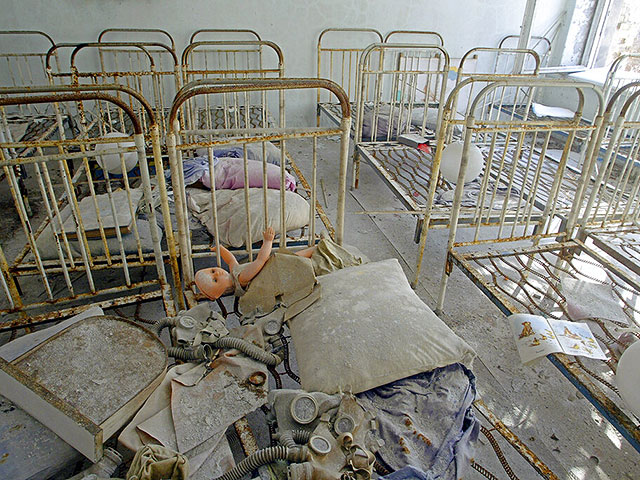 Детские игрушки и противогазы, покрытые радиоактивной пылью, на кроватях в заброшенном детском саду в городе-призраке Припять. 10 марта 2006 года
