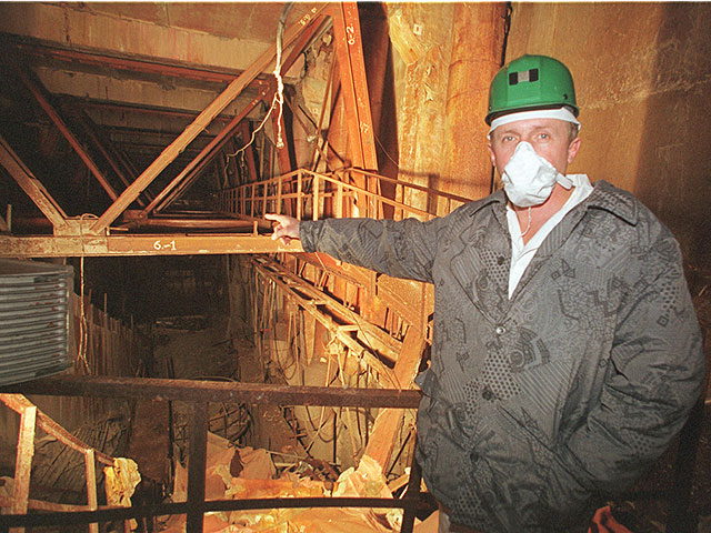 Исследователь указывает на поврежденный реактор № 4 на Чернобыльской атомной электростанции. 2000 год