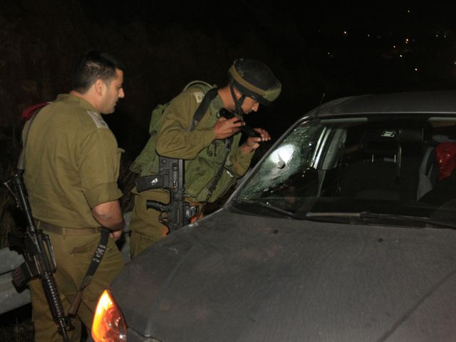 Израильские солдаты изучают автомобиль, поврежденный камнем