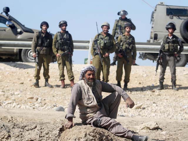Израильские военные и один из местных жителей наблюдают за происходящим в Эйн-Хаджле. 6 февраля 2014 года