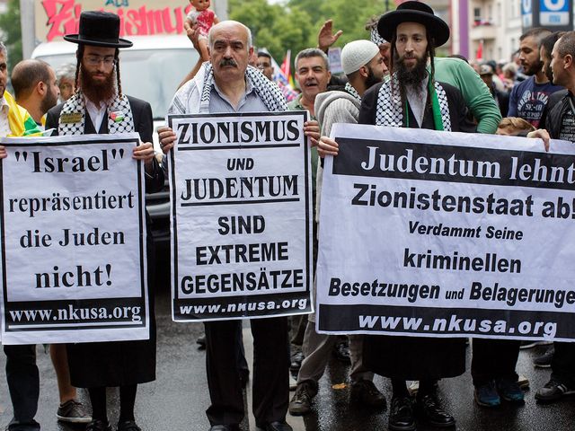 Надписи на плакатах: "Израиль не представляет евреев", "Иудаизм и сионизм полностью противоположны", "Долой сионистское государство преступников и оккупантов"