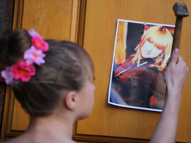 Активистка FEMEN Ульяна Бляшин прибивает портрет своей сестры Любы ко входу в здание СБУ. Киев, 1 декабря 2014 года