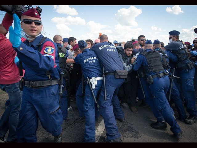 Полиция пытается сдержать мигрантов, рвущихся к близлежащей автомагистрали. Венгрия, 7 сентября 2015 года