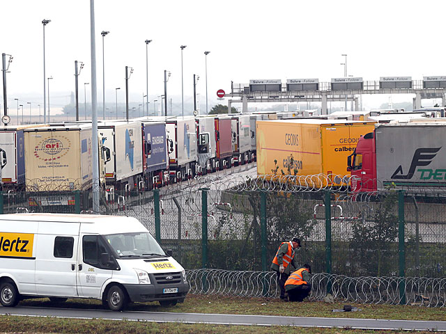 Рабочие укрепляют забор на стоянке грузовиков в Кале