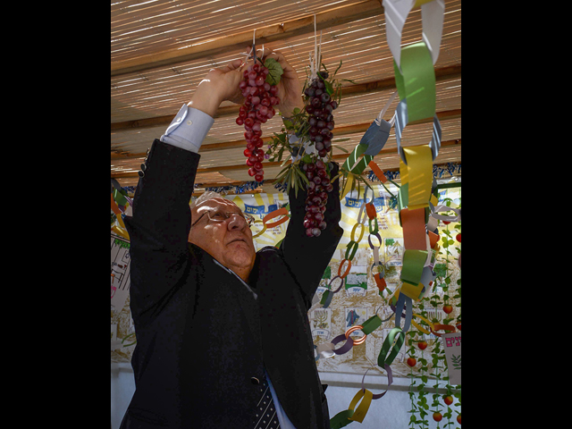 Президент Израиля Реувен Ривлин украшает сукку