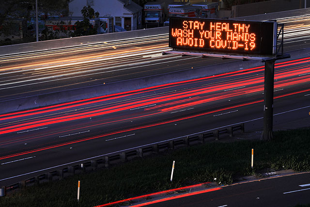 Надпись на дорожном указателе: "Будьте здоровы, мойте руки, избегайте COVID-19"