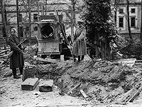 Два солдата Красной Армии на заднем дворе рейхсканцелярии указывают на предположительное место, где было найдены останки Гитлера, июль 1945 года