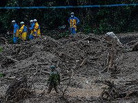 Спасательная служба и солдат сил самообороны Японии работают на месте оползня вызванного проливным дождем, 7-ого июля 2020 в Цунаги, Япония