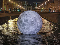 Люди смотрят на шар с изображением поверхности Луны, инсталляцию для "Фестиваля огней", в воде Обводного канала, Санкт-Петербург, Россия