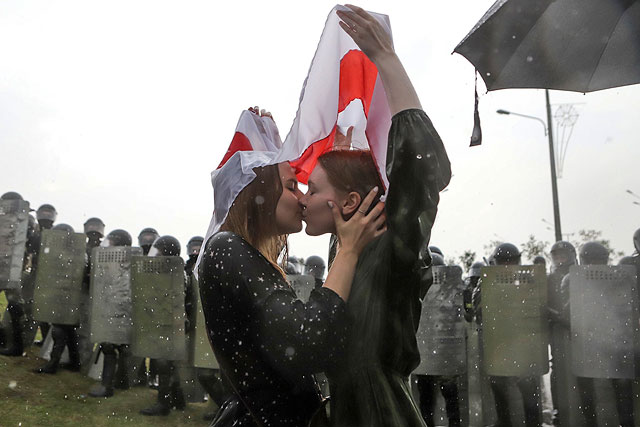 Две девушки целуются под старым белорусским национальным флагом возле Дворца Независимости в Минске, Беларусь, 30 августа 2020 года