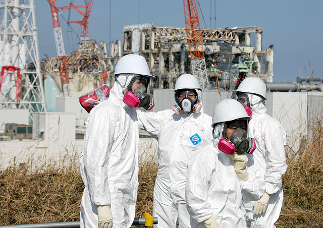 Представитель СМИ в сопровождении сотрудников TEPCO в защитных костюмах осматривает здания энергоблоков 3 и 4 пострадавших от цунами. 28 февраля 2012 года