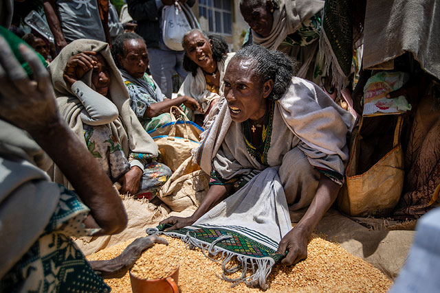 Женщина спорит с другими по поводу распределения гороха, раздаваемого Обществом милосердия Тыграя в городе Агула на севере Эфиопии, 8 мая 2021 года. По данным AP в раздираемом войной Тыграе многие умирают от голода