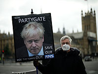 Протестующий против Консервативной партии держит плакат с изображением премьер-министра Великобритании Бориса Джонсона у здания парламента в Лондоне
