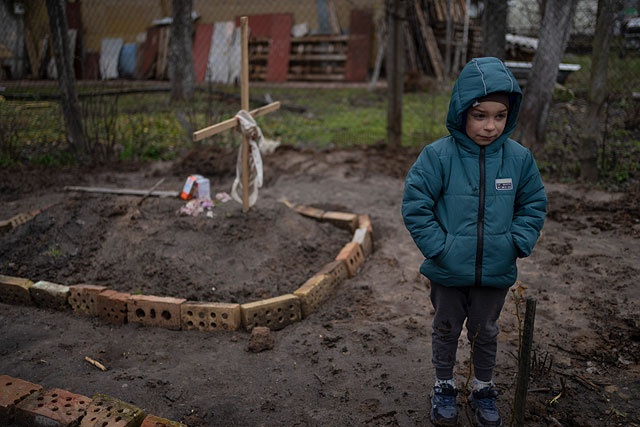 6-летний Влад Танюк во дворе своего дома возле могилы своей матери Марины, окраина Киева, 4 апреля 2022 года
