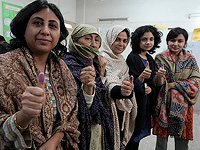Женщины показывают, что проголосовали на избирательном участке во время парламентских выборов в Карачи, Пакистан