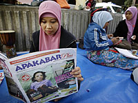 Индонезийская домработница читает газету с историей издевательств над Эрвианой Сулистьянингсих