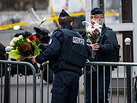 Полицейские относят переданные прохожими цветы к кошерному магазину в Порт-де-Винсен. Париж, 10.01.2015